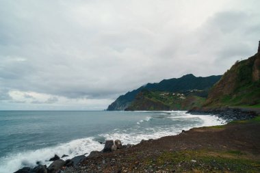 Su sıçratan dalga Madeira Adası 'nın kayalık sahillerinde oturuyordu.