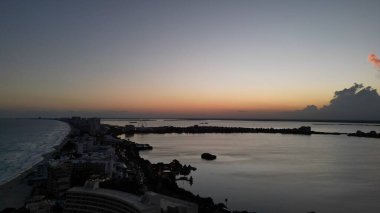 Gün batımında binalar ve suyla çevrili Miami şehir manzarası.