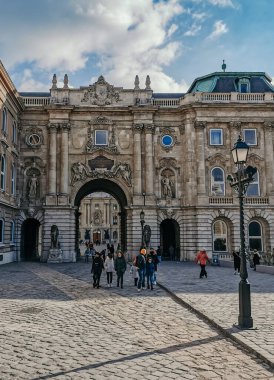 Güneşli bir günde Budapeşte Tarih Müzesi 'nin dikey görüntüsü. Orada turistler yürüyor, gökyüzü bulutlu.