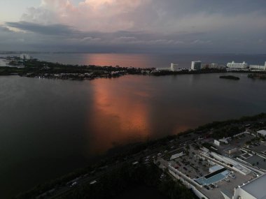 Gün batımında binalar ve suyla çevrili Miami şehir manzarası.