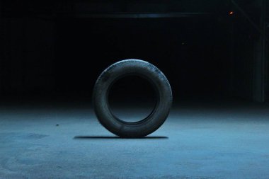 Karanlık bir arka planda yerde bir araba lastiği.