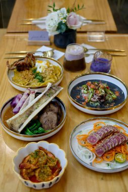 Uzun, ahşap bir masaya yakın çekim. Çeşitli lezzetli Filipin yemekleri sergileniyor.