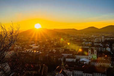 Dağların ve şehir binalarının üzerinde altın bir gün doğumu