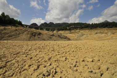 Arka planda büyük bir köprü manzaralı kumlu bir manzara.