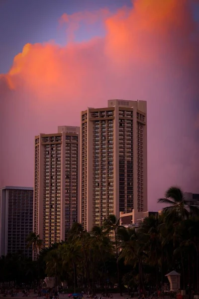 日没時に後ろにオレンジ色の雲のある都市に位置する現代の高層ビルの垂直ショット — ストック写真