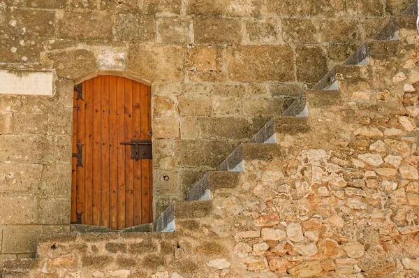 stock image A view of stairs in front of an old wooden door in a stone wall in the scenic city of Denia, Spain