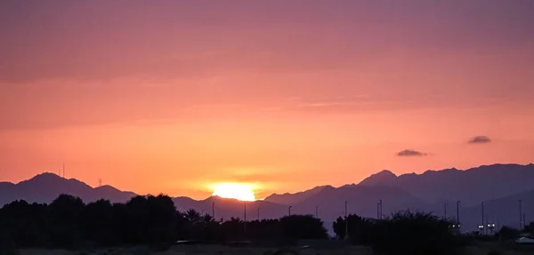 Μια Σειρά Από Βουνά Ένα Όμορφο Πορτοκαλί Ηλιοβασίλεμα Στο Παρασκήνιο — Φωτογραφία Αρχείου