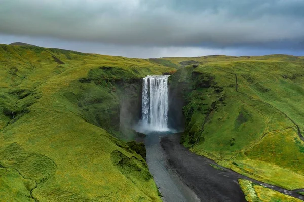Krajobraz Wodospadu Skogafoss Otoczony Zielenią Pod Zachmurzonym Niebem Islandii — Zdjęcie stockowe