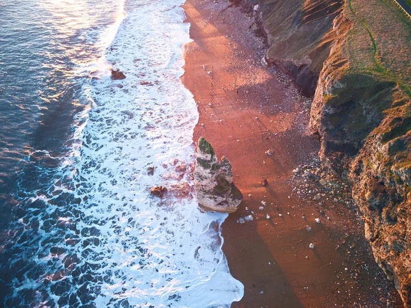 Kumlu Bir Kıyı Şeridini Kayalarla Yıkayan Köpüklü Bir Gelgit — Stok fotoğraf