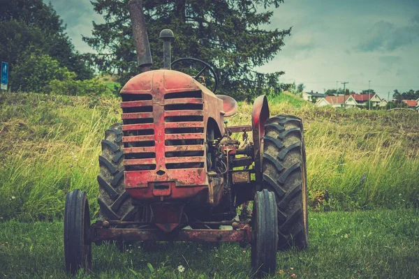 田里的一辆旧的橙色拖拉机 四周是室外牧场 — 图库照片