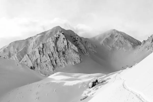 Ένα Γκρι Πλάνο Χιονισμένων Βουνών Κάτω Από Ένα Συννεφιασμένο Ουρανό — Φωτογραφία Αρχείου