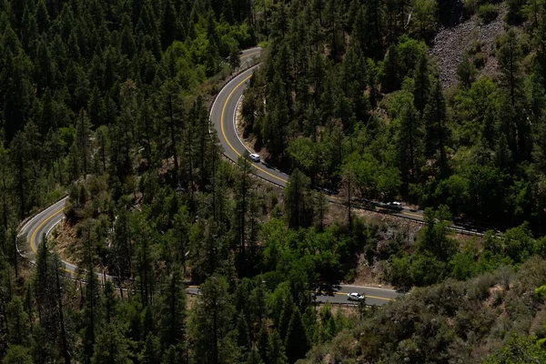 一架无人驾驶飞机在一座山上的绿林之间的公路上盘旋 — 图库照片