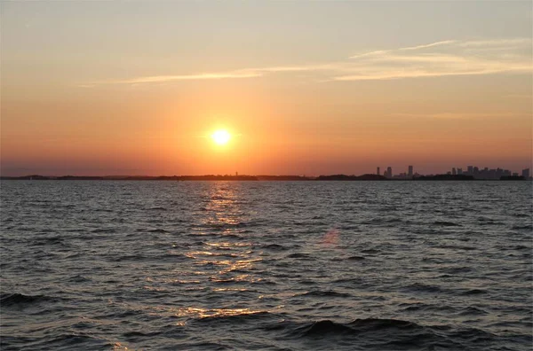 stock image A beautiful sunset sky over the sea with a city skyline in the horizon