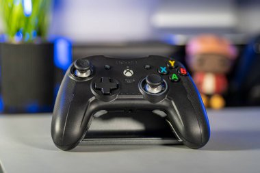 Bir kızın elinde siyah bir nacon xbox kumandası ve tırnakları boyalı.