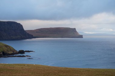 Bulutlu bir günde okyanus kenarında kayalık bir ada.