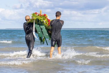 Dalgıç kıyafetli ve çiçekli iki adam denize giriyor.