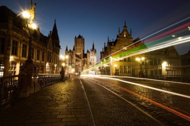 Sint-Michielsbrug 'un uzun bir pozu, Gent Belçika' daki alacakaranlıkta Leie nehrinin üzerinde taş bir kemer köprüsü.