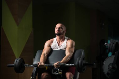 Ağırlık egzersizi yapan kaslı bir adam. Spor salonunda halterli biblolar için.