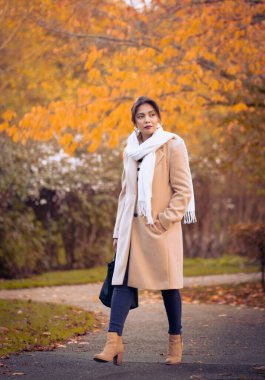 Bir sonbahar sabahı parkta yürüyen zarif bir kadın.