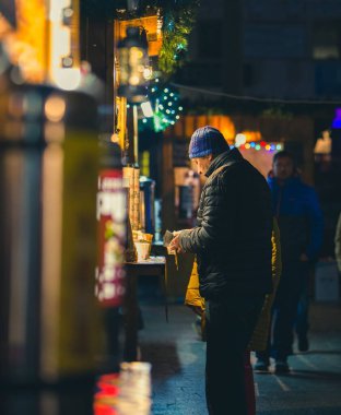 Poprad 'taki Noel pazarında yetişkin bir adam kahvesini bulanık bir ön planla ödüyor, Slovakya.