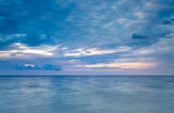 ラダム湾の静かな海の上に沈む夕日の柔らかい紫色の空に濃い青の雲の豪華な景色 — ストック写真