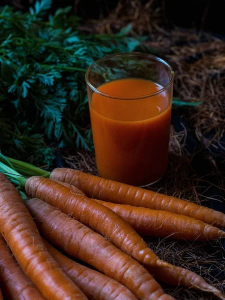 在一杯胡萝卜汁旁边 一垂直镜头的胡萝卜束 — 图库照片