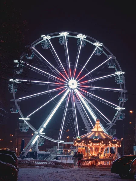 スロバキアのコスイスで夜にライトアップされた観覧車とカルーセルを備えた遊園地の垂直ショット — ストック写真