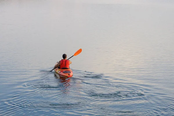 Mężczyzna Kajaku Wiosłujący Spokojnym Jeziorze Pod Łagodnym Oświetleniem Zachodzie Słońca — Zdjęcie stockowe