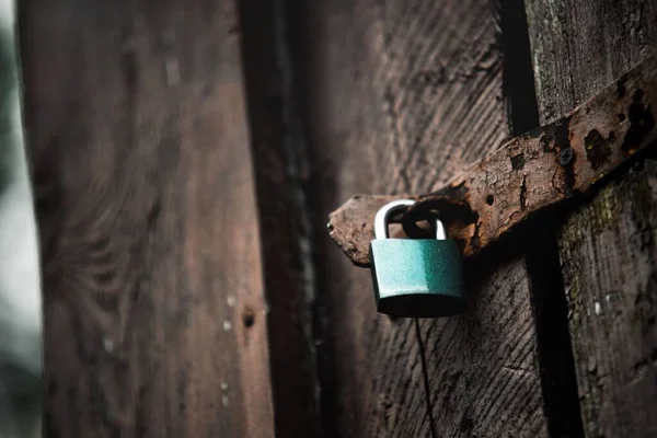 緑の南京錠でロックされている古い木製のドアのクローズアップショット — ストック写真