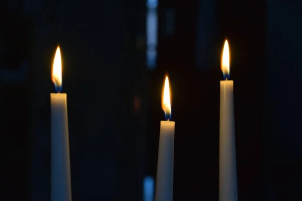 三支点燃的蜡烛在黑暗的房间里缓缓燃起的特写镜头 — 图库照片