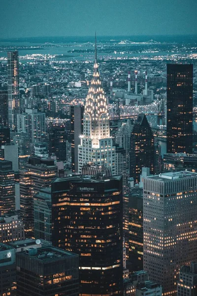 夜间被摩天大楼环绕的明亮的克莱斯勒大楼的垂直截图 — 图库照片