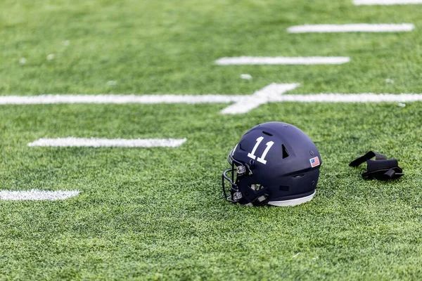第11アメリカンフットボールヘルメットと白い手袋のペアが芝生の上に横たわっている — ストック写真