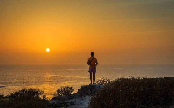 在明亮的落日的天空下 男人欣赏大海的轮廓 — 图库照片