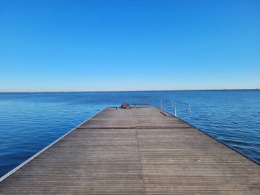 Sakin, masmavi bir deniz ile çevrili bir atlama platformu berrak bir gökyüzünün altında.