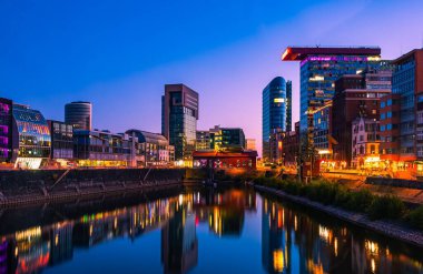 Alacakaranlıkta Düsseldorf limanının ufuk çizgisi suya yansıdı.