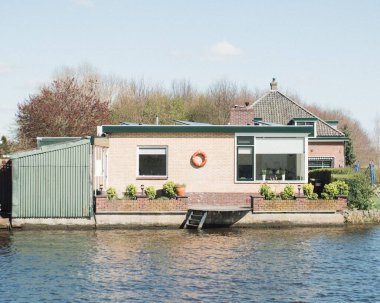 Güneşli bir günde nehir kenarında can yeleği olan modern bir ev.