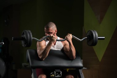 Ağırlık egzersizi yapan kaslı bir adam. Spor salonunda halterli biblolar için.