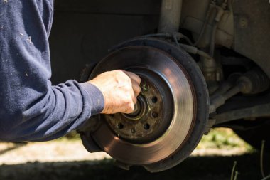 Bir arabanın fren sistemini tamir eden ve temizleyen tamircinin ellerine yakın çekim.