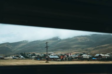 Tepelerin yakınındaki kırsal evler küçük pencereden görülebiliyor.