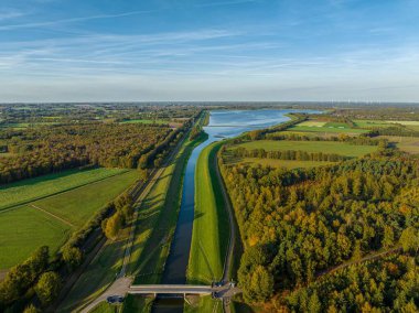 Köydeki yemyeşil ağaçlarla çevrili dar nehrin havadan çekilmiş görüntüsü.