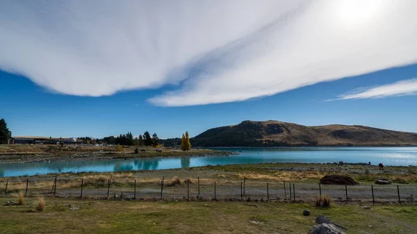 Una Panoramica Lago Circondato Verdi Campi Colline Sotto Cielo Blu — Foto Stock