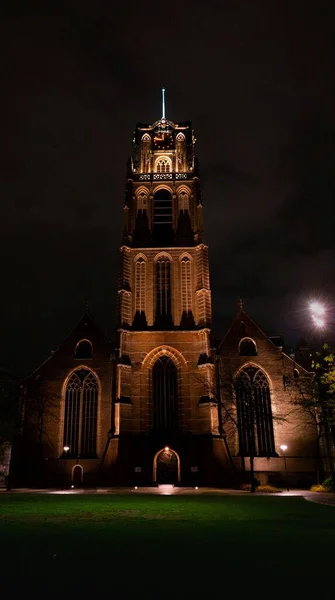 ロッテルダムの夜にライトアップされた歴史的な教会の塔の垂直ショット — ストック写真