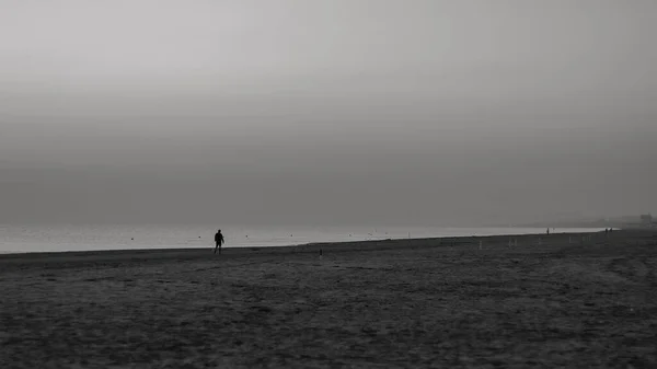 Szara Skala Człowieka Stojącego Samotnie Plaży Ponurym Tle Nieba — Zdjęcie stockowe
