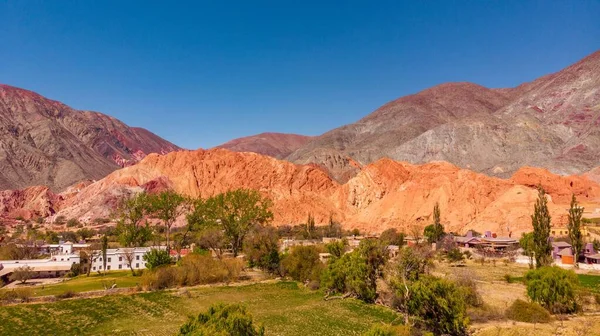 Güneşli bir günde, Arjantin 'in Jujuy kentindeki Purmamarca kasabasında, dağ ve renkli tepelerle bir manzara.