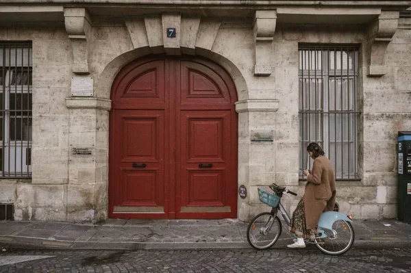 Eine Frau Auf Einem Fahrrad Wartet Vor Der Roten Holztür — Stockfoto