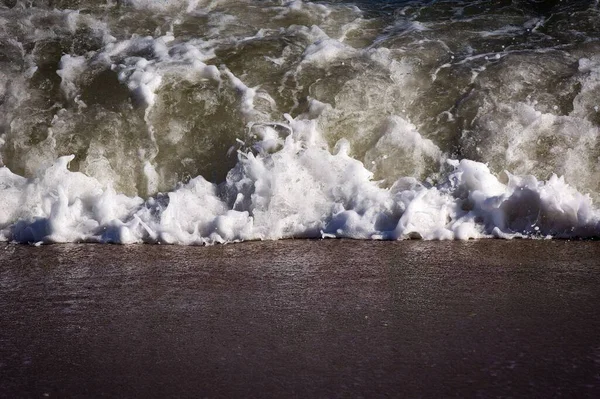 海面上起泡的海浪在沙滩上翻滚 拍打着近照 — 图库照片