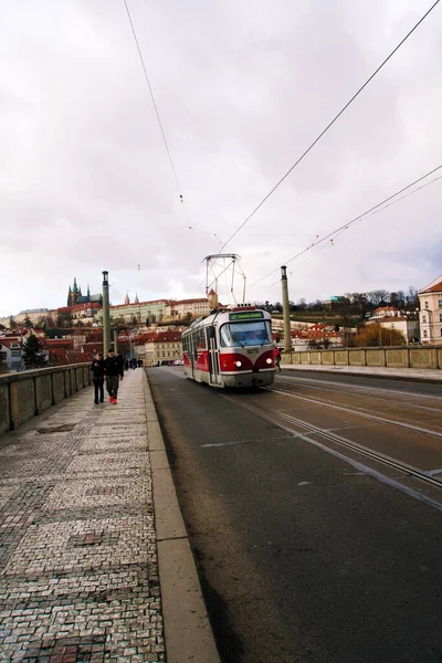プラハのマネス橋を歩いている人々の垂直ショット 午後にトラムが通過するチェコ共和国 — ストック写真