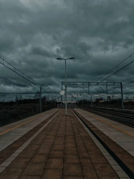 Pion Pustej Stacji Kolejowej Zegarem Tle Pod Ciemnymi Burzliwymi Chmurami — Zdjęcie stockowe