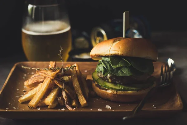 stock image A closeup shot of a wooden plate with a burger and french fries served with beer