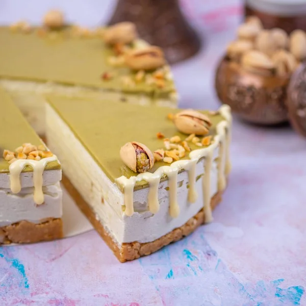 ピスタチオクリームをピスタチオで飾り バニラクリームを背景にしたチーズケーキのクローズアップ — ストック写真